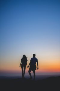 man and woman holding hands in silhouette photography